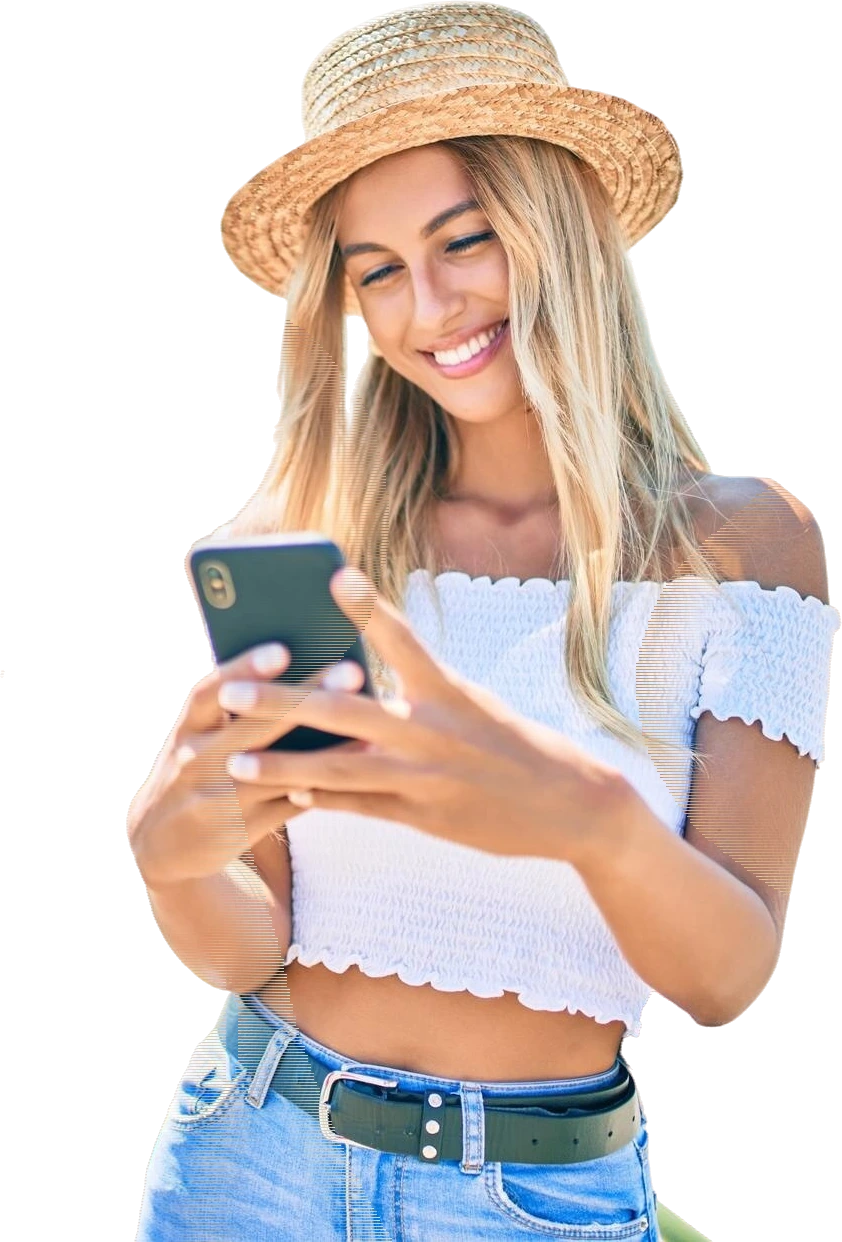 A smiling traveller messages a New Zealand tour operator from her phone, outdoors in the sun